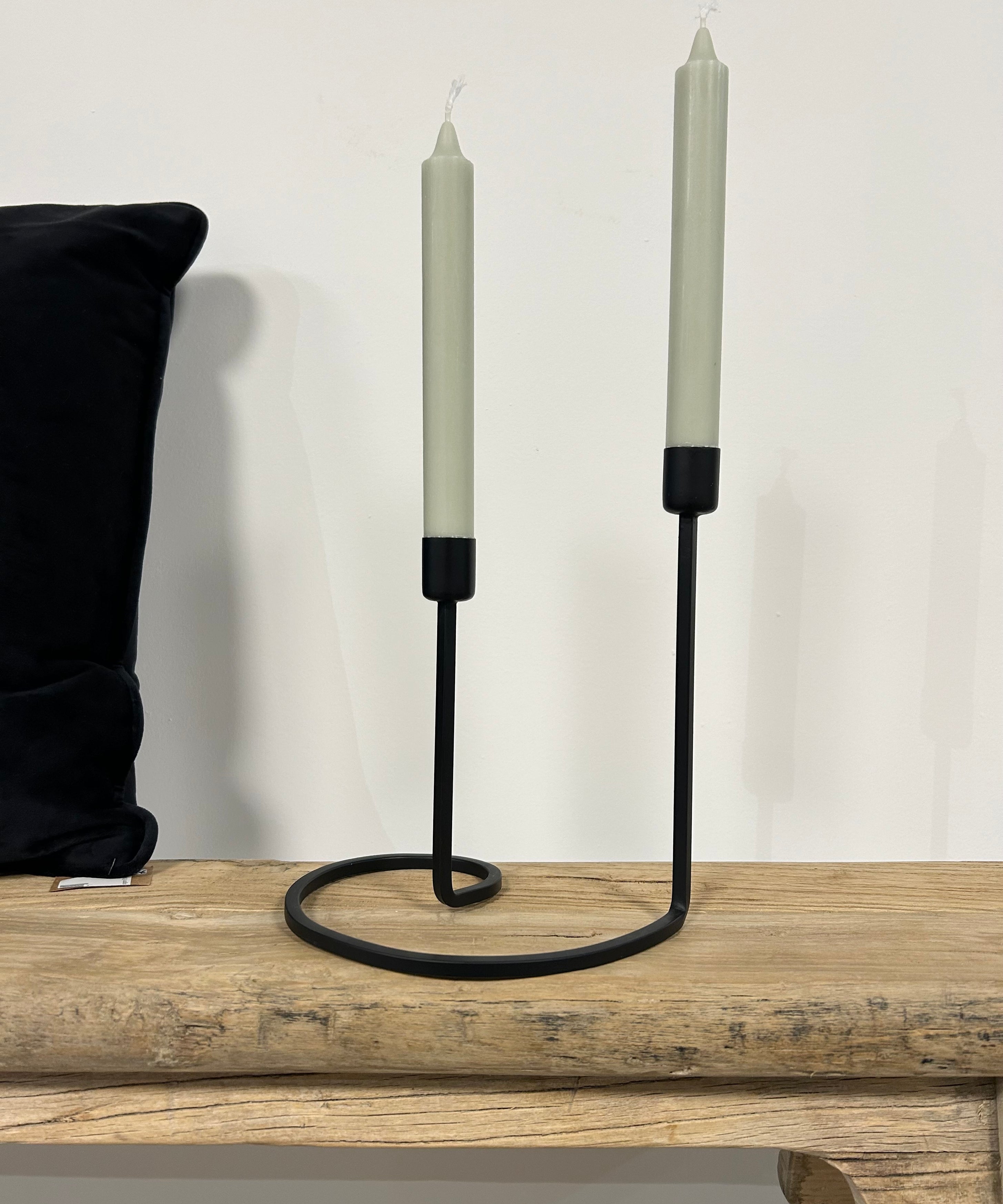 Bougeoir noir de style scandinave avec deux bougies chandelle vert pastel, posé sur un banc en bois naturel Inde