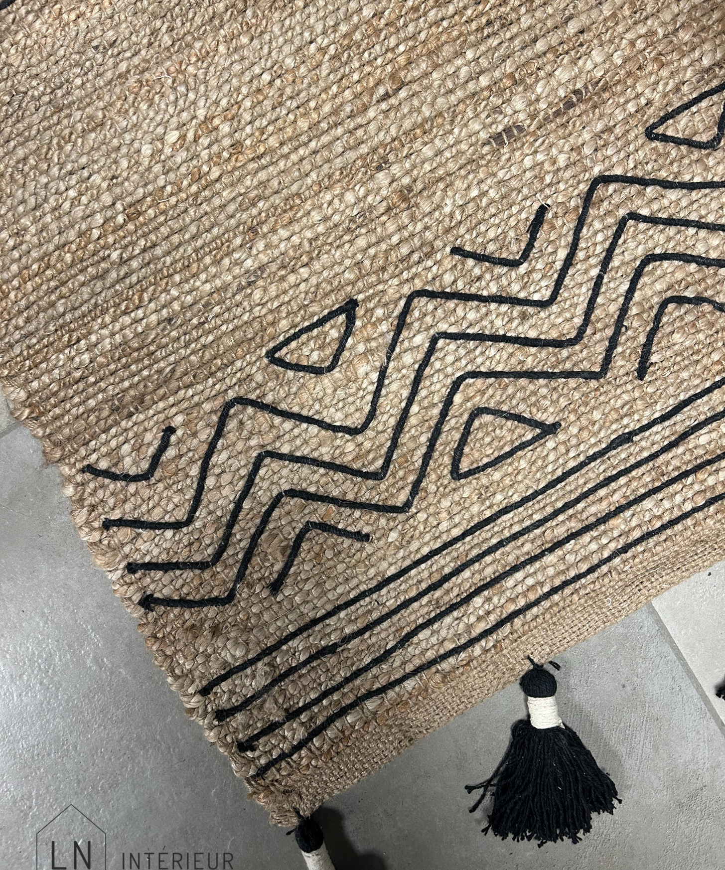 tapis de couloir ou descente de lit noir et naturel avec pompons dans un style ibiza